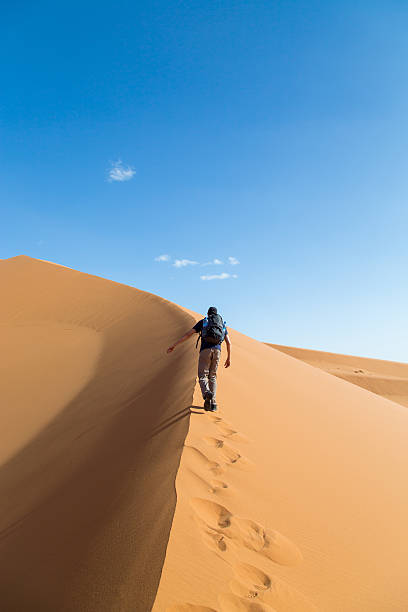 istock One person climbing big dune in the desert 532010275