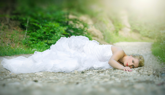 blond hair bride lying in nature.