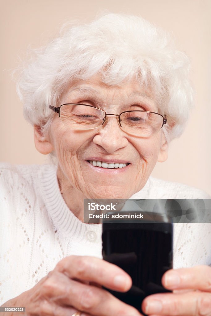 Senior Woman Smiling As She Texts on a Smart Phone A smiling 87 year old woman using a smart phone to send a text message. Mobile Phone Stock Photo