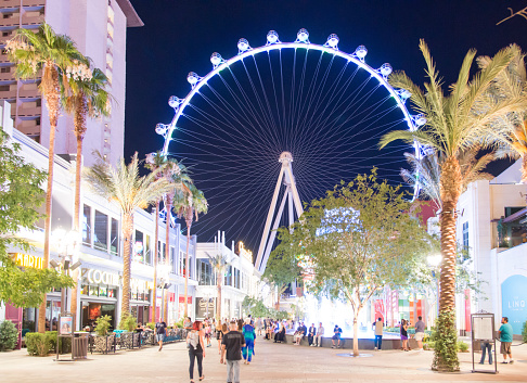 Las Vegas, Nevada, USA - June 7, 2014: People walking on the street next to retail shops and restaurants in front of the High Roller Ferris Wheel in Las Vegas during late night in the summer.