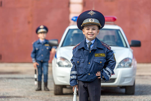 Little boy in police uniform with his friend standing near police car