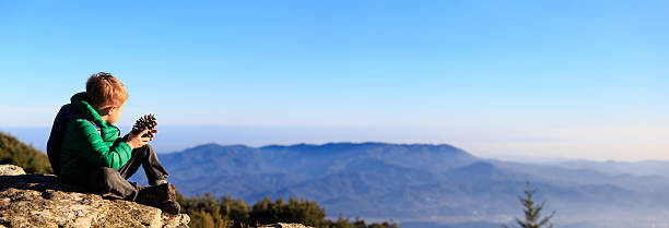 istock little boy hiking in scenic mountains looking at pine cone 532027534