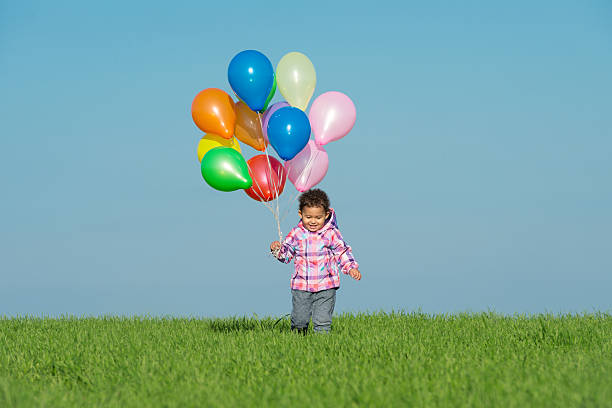 笑顔小さな女の子保持風船ます。 - balloon moving up child flying ストックフォトと画像