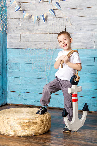 istock little boy standing and holding an anchor 532038042