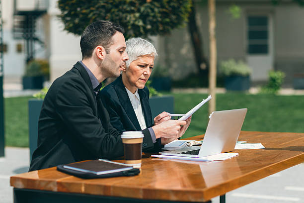 istock Businesspeople Sitting Outdoors In Tech Park And Using Laptop. 532042536