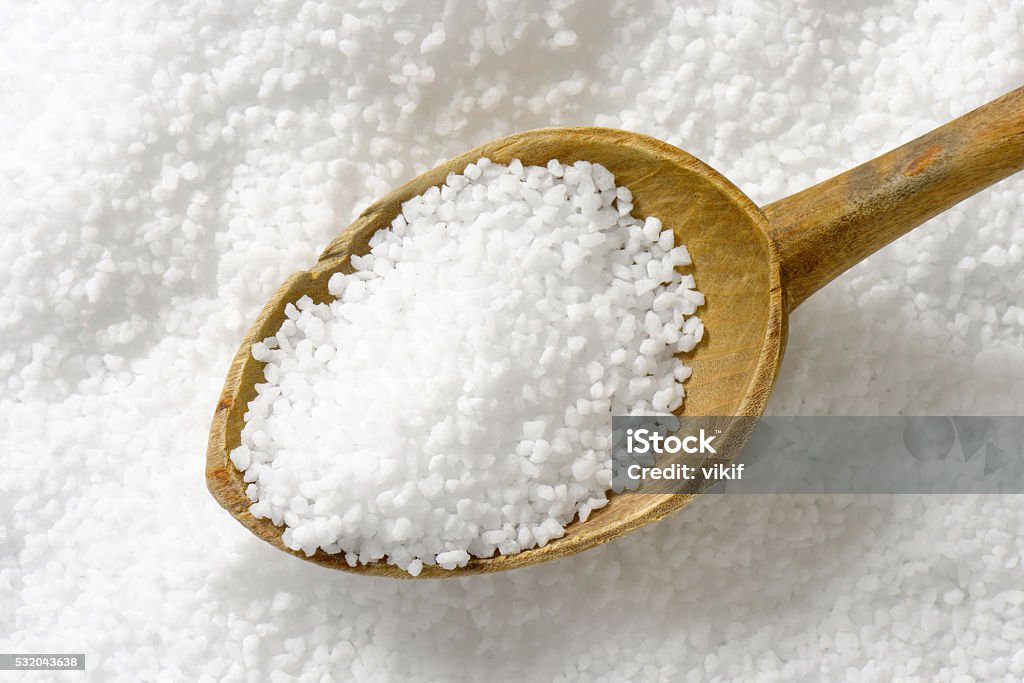 Coarse grained salt Detail of coarse grained salt and wooden spoon Alternative Medicine Stock Photo