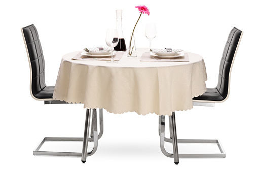 Restaurant table with two plates and a bottle of red wine isolated on white background