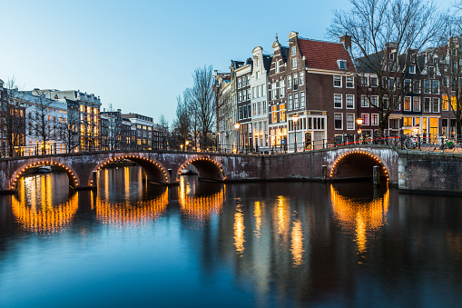 A view of the bridges at the Leidsegracht and Keizersgracht canals intersection in Amsterdam at dusk.