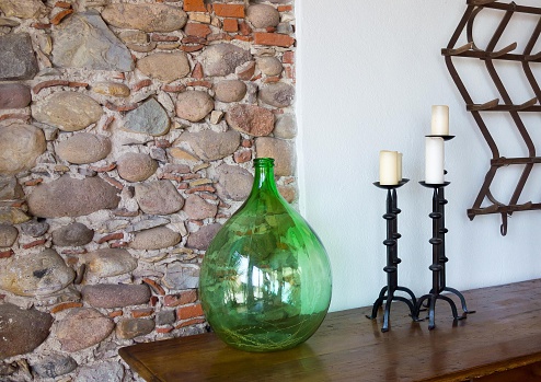 fragment of a room interior with a glass vase and with forged candlesticks a closeup and a stone wall