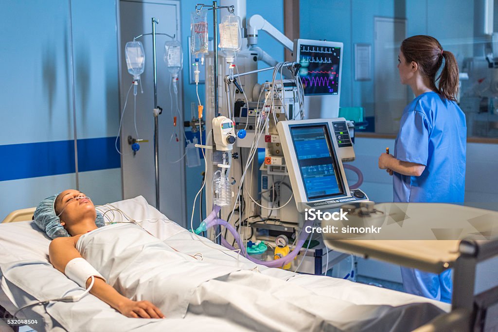 Injured women in operating theatre Injured patient on operating bed while nurse working in operating theatre. Intensive Care Unit Stock Photo