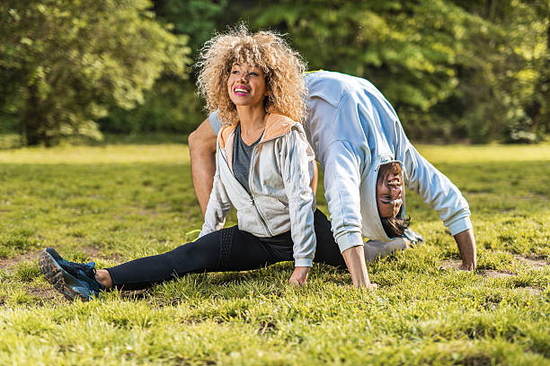 sportowe młoda para robi rozciąganie i ćwiczenia w parku. - yoga flexibility two people women zdjęcia i obrazy z banku zdjęć