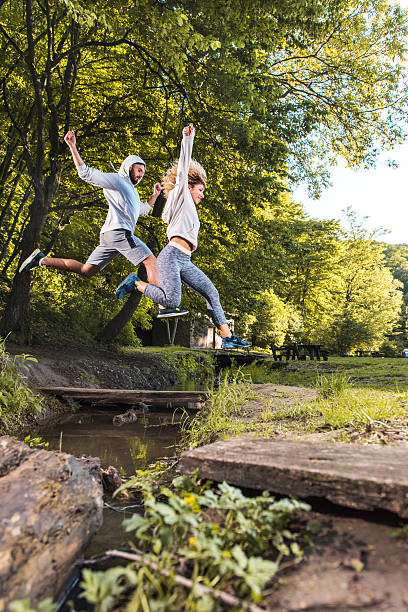 jóvenes atletas salto de la corriente en el parque. - jumping women running vitality fotografías e imágenes de stock