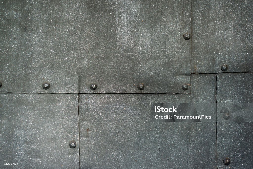 Ancient Cast Iron Door Background Ancient Cast Iron Door Background. Part of the back entrance of a medieval castle. The gate is made out of cast iron sheet metal and put together by handforged nails or rivets. The metal sheets have a dark grey color. The same kind of gate is also common at the back entrances of most old european churches. These doors are secure and made to last for many centuries. Medieval Stock Photo