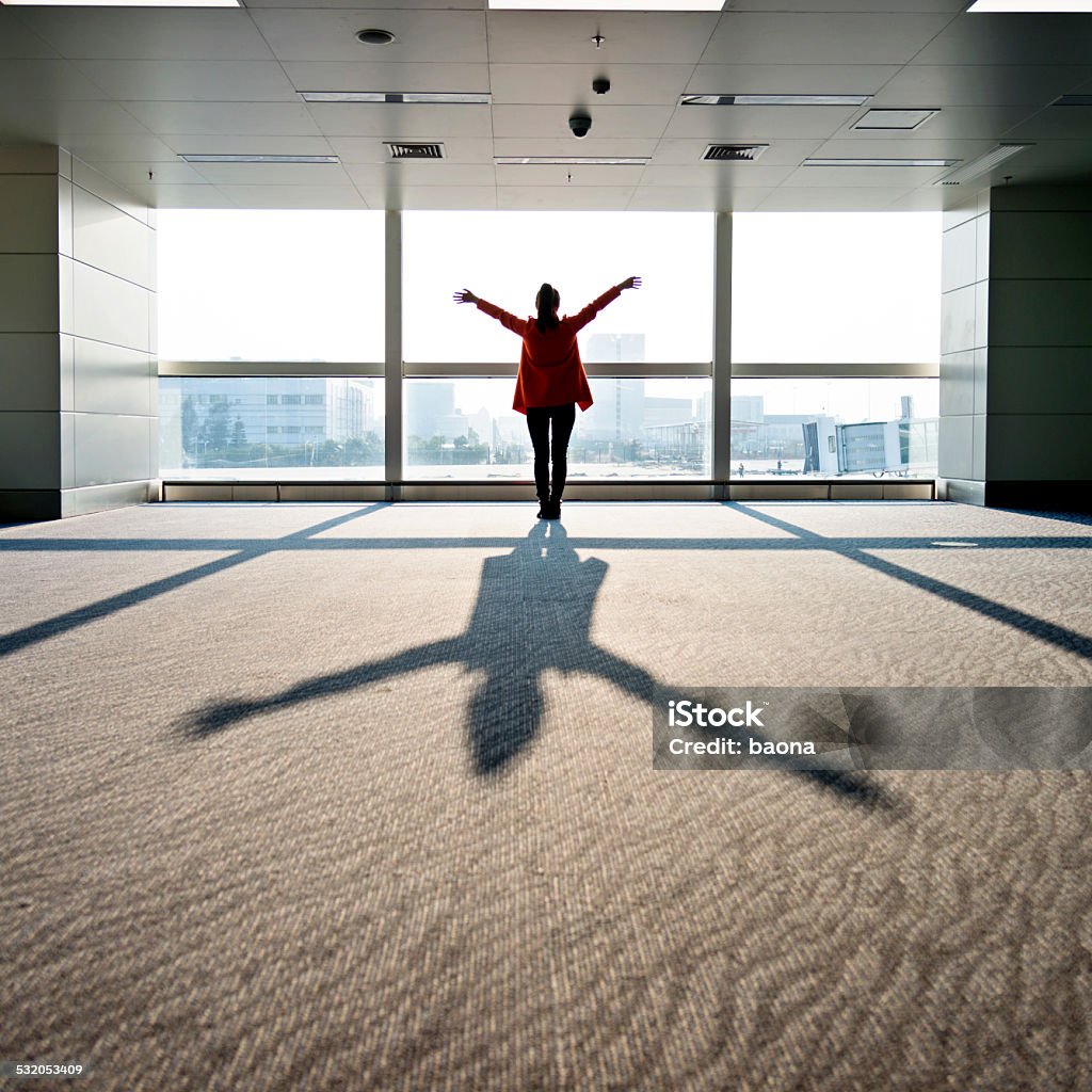 expressing freedom Woman standing in front of window and arms outstretched, expressing freedom. Business Stock Photo