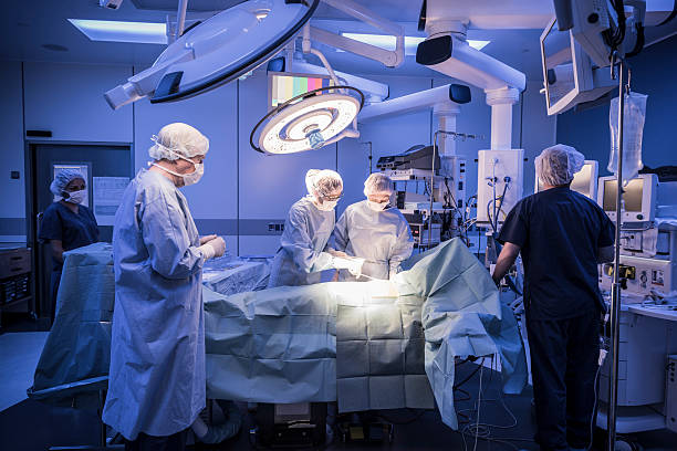 team von chirurgen betrieb auf patienten im krankenhaus - operationssaal stock-fotos und bilder