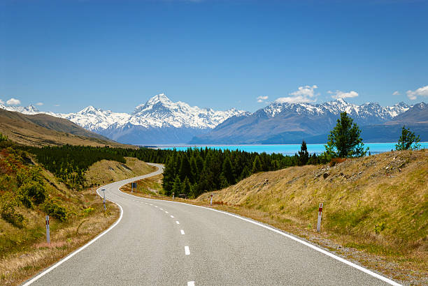 istock Scenic road winds along glacial blue lake towards mountain range 532054599