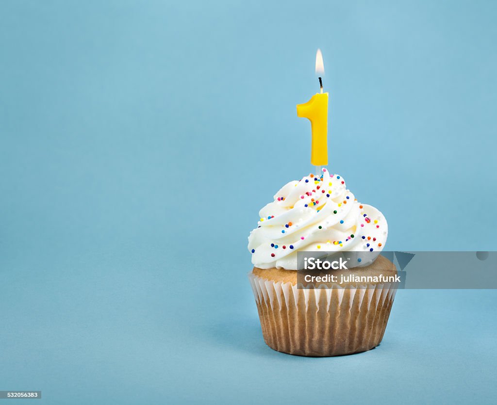 Birthday Cupcake A birthday cup cake with buttercream icing,  sprinkles and a lit number one birthday candle. Number 1 Stock Photo