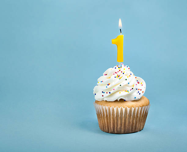 Birthday Cupcake A birthday cup cake with buttercream icing,  sprinkles and a lit number one birthday candle. cupcake candle stock pictures, royalty-free photos & images