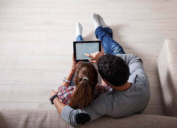 Young couple sitting  in the living room and using tablet stock photo
