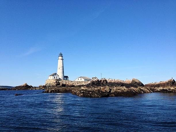 Boston Light, Boston Massachusetts Boston Light, looking towards the Boston Skyline. America's oldest Lighthouse located on Little Brewster Island in Boston Harbor.  boston harbor stock pictures, royalty-free photos & images