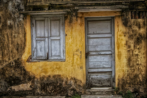 Blue door and shuttered windows of an old yellow house in Hoi An, Vietnam.