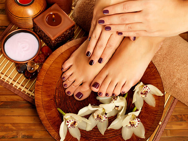 female feet at spa salon on pedicure procedure Closeup photo of a female feet at spa salon on pedicure procedure. Female legs in water decoration  the flowers. toenail stock pictures, royalty-free photos & images
