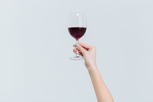 Female hand holding glass with wine isolated on a white background