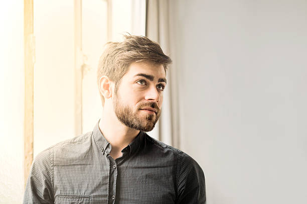 istock Thoughtful young man standing near window 532110456