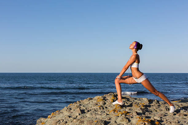 Young woman practicing stretching exercises at the beach
