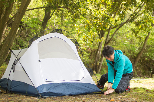 Mature man camping and enjoying setting up a tent