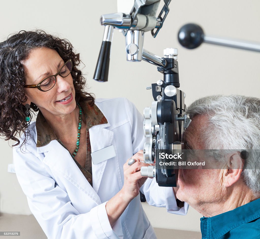 Optometrist with patient Optometrist giving eye exam to senior patient 2015 Stock Photo