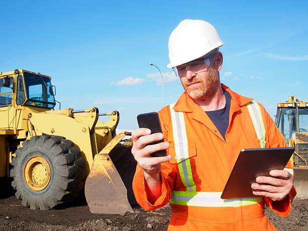 trabalhador da construção civil e computador e tecnologia do telefone - industrial equipment trackhoe construction site construction vehicle imagens e fotografias de stock