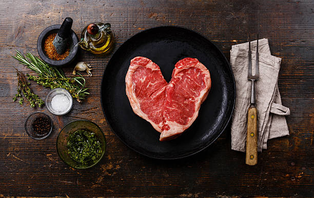 forma de corazón sin procesar de carne bistec en sartén - steak meat fork beef fotografías e imágenes de stock