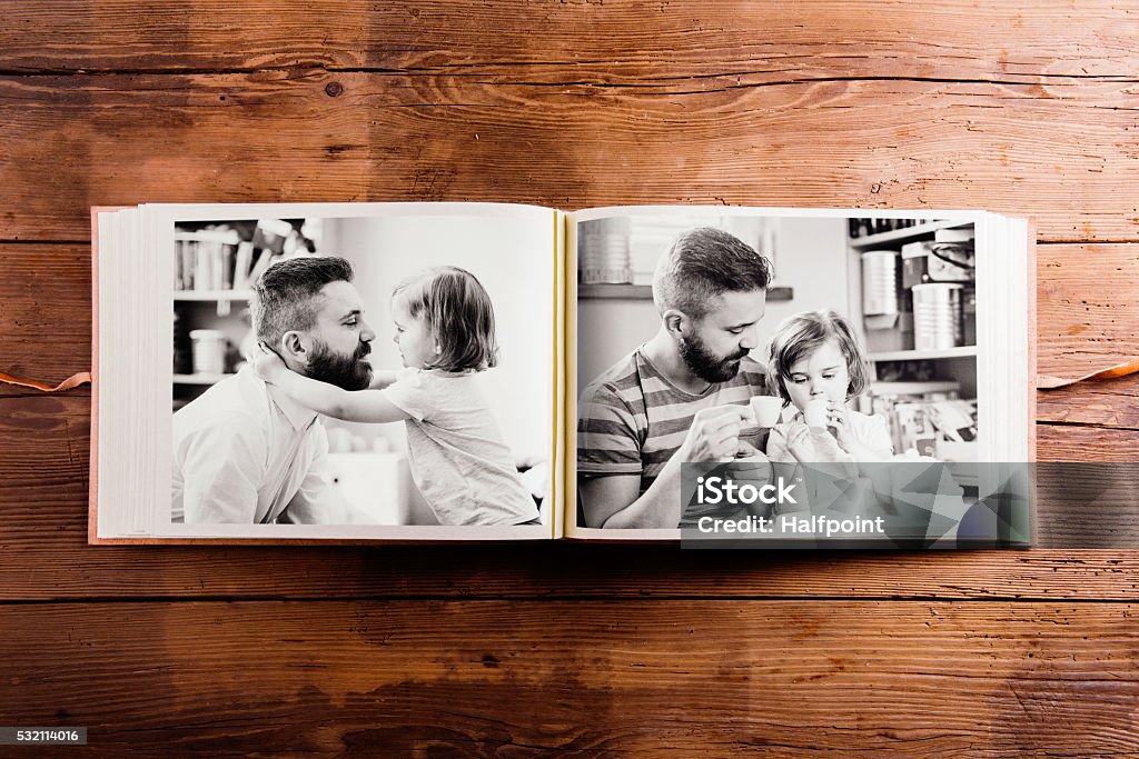 Fathers day composition. Photo album, black-and-white pictures. Fathers day composition. Photo album, black-and-white pictures. Studio shot on wooden background. Photographic Print Stock Photo