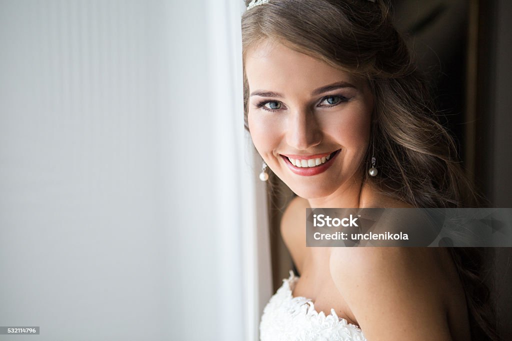 happy bride smiling at the camera Beautiful smiling Bride wedding Portrait with wedding hairstyle, Wedding dress. Wedding decoration. soft selective focus. gorgeous young woman in hotel room Bride Stock Photo