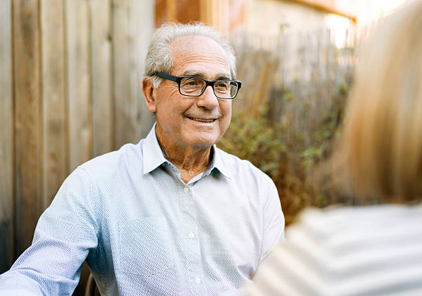 heureux homme senior parler avec femme en arrière-cour - homme 65 ans photos et images de collection