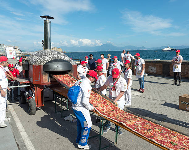 Guinnes World record pizza long 2 km Naples, Italy - May 18, 2016: 250 pizza chefs from around the world in Naples beat the Guinness world record for long pizza margherita circa 2 Km. The super pizza of about 1,850 meters, exceeding the previous record of 1,595 meters, reached June 20, 2015 at Expo in Milan. guinnes stock pictures, royalty-free photos & images