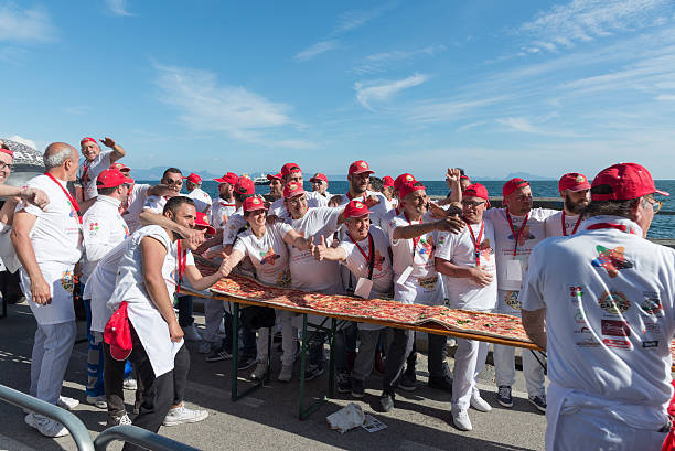 Guinnes World record pizza long 2 km Naples, Italy - May 18, 2016: 250 pizza chefs from around the world in Naples beat the Guinness world record for long pizza margherita circa 2 Km. The super pizza of about 1,850 meters, exceeding the previous record of 1,595 meters, reached June 20, 2015 at Expo in Milan. guinnes stock pictures, royalty-free photos & images