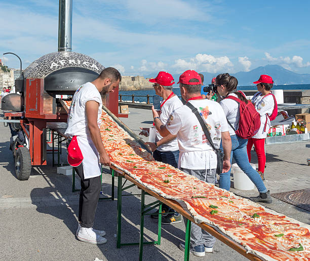 Guinnes World record pizza long 2 km Naples, Italy - May 18, 2016: 250 pizza chefs from around the world in Naples beat the Guinness world record for long pizza margherita circa 2 Km. The super pizza of about 1,850 meters, exceeding the previous record of 1,595 meters, reached June 20, 2015 at Expo in Milan. guinnes stock pictures, royalty-free photos & images