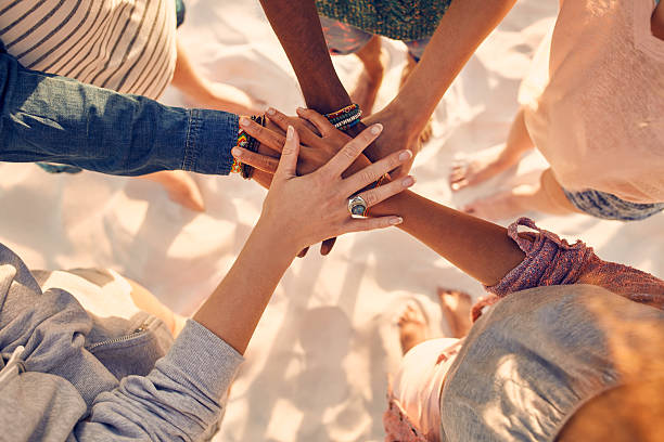 Hands of young people on stack at beach Closeup image of hands of young people with on stack. Group of mixed race friends on the beach with their hands stacked. stacked hands photos stock pictures, royalty-free photos & images