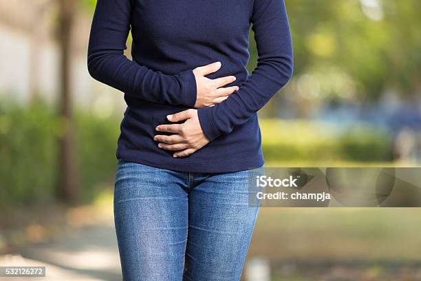 Woman Has Stomach Ache At Park Stock Photo - Download Image Now - Abdomen, Stomachache, Stomach