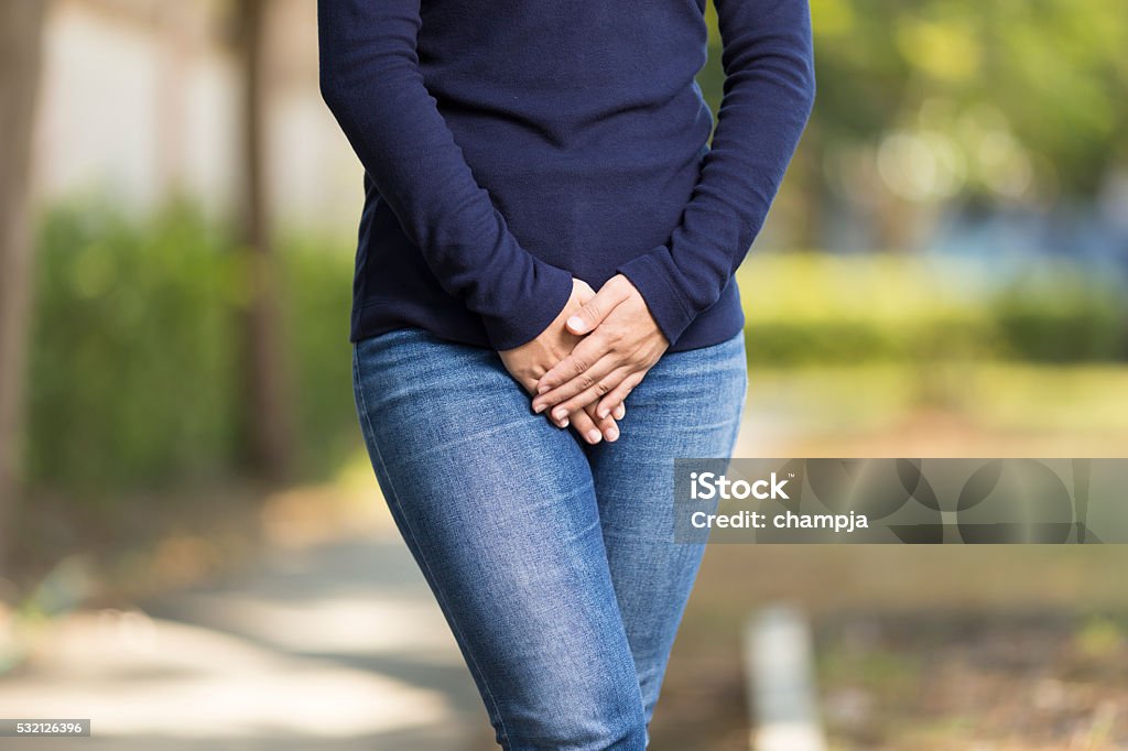 Woman with Hands Holding her Crotch Urinating Stock Photo