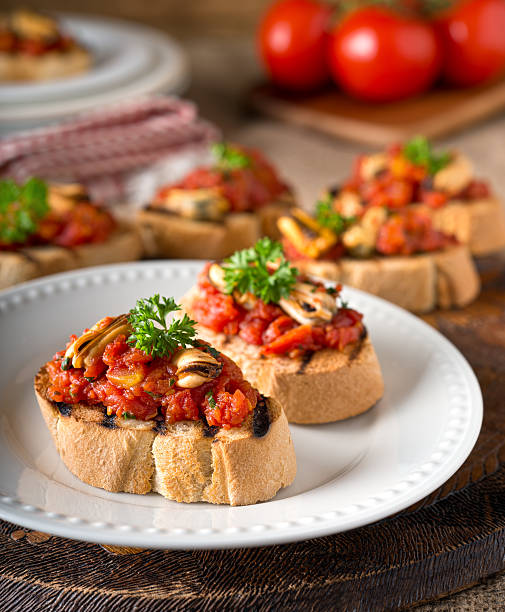 Mussels Bruschetta Delicious mussels bruschetta with tomato, parsley, olive oil, and garlic on grilled french bread. bruschetta stock pictures, royalty-free photos & images