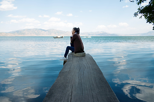 Woman sitting on lakeside jetty.