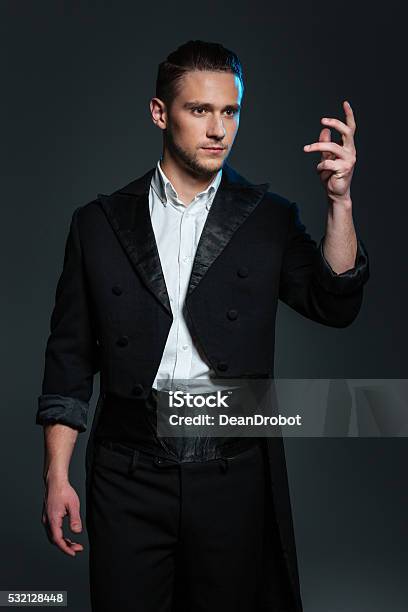 Serious Young Man Magician In Black Tail Coat Showing Tricks Stock Photo - Download Image Now