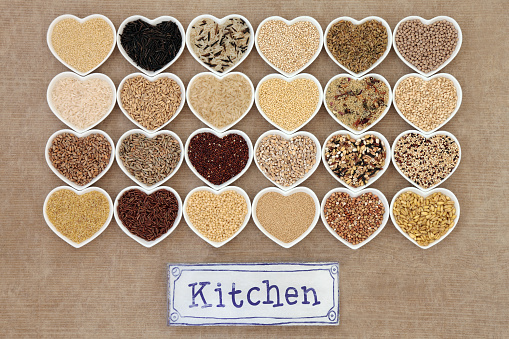 Healthy grain food selection in heart shaped porcelain bowls with old metal kitchen sign forming an abstract background.