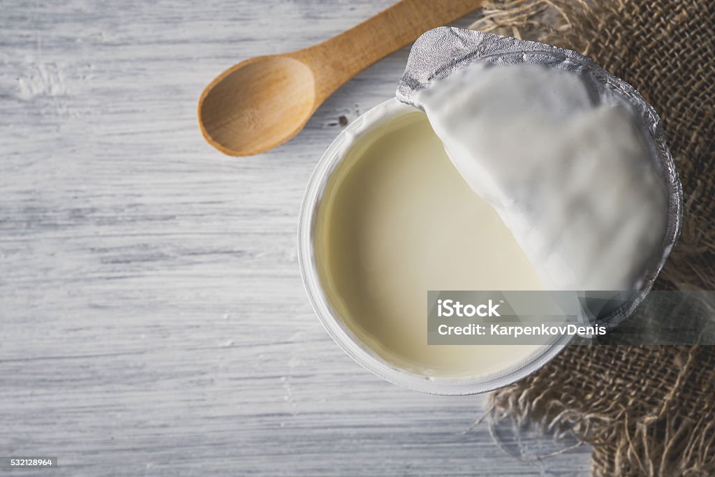 Natural yogurt on the white wooden table top view Natural yogurt on the white wooden table with napkin and spoon top view Dairy Product Stock Photo