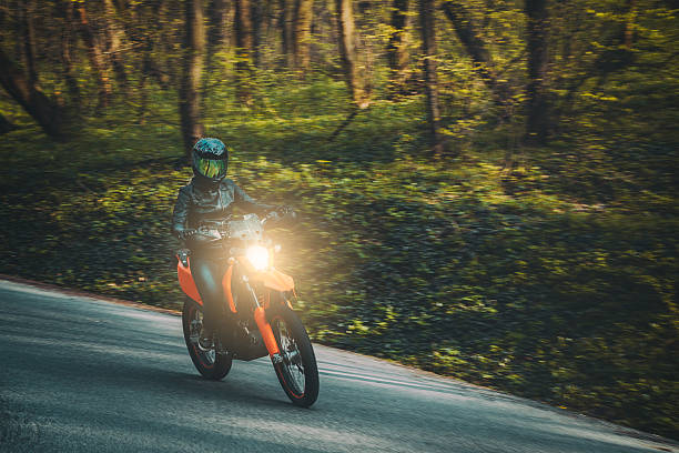 A mature man is riding on his cruiser style motorcycle on the road through the nature