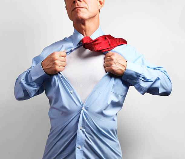 Superhero. Mature businessman tearing his shirt off over white background stock photo