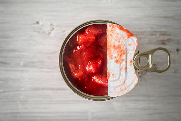 cortado tomates en encapsulado metálico en mesa de madera y vista - alimento conservado fotografías e imágenes de stock